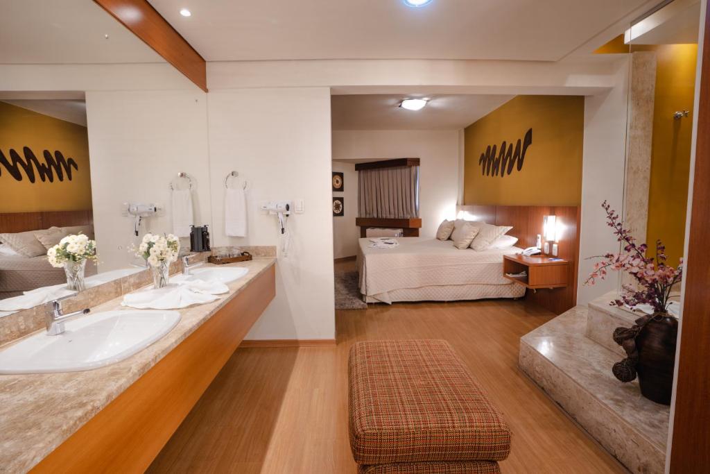 a bathroom with a sink and a living room at Hotel Caiuá in Umuarama