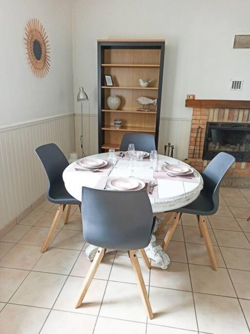 a dining room with a table with chairs and a fireplace at Maison de pêcheur rénovée (new) in Ploubazlanec