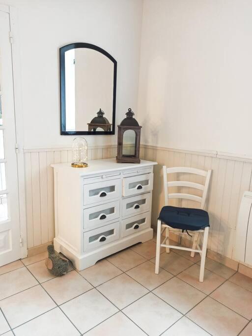 a white dresser with a mirror and a chair at Maison de pêcheur rénovée (new) in Ploubazlanec
