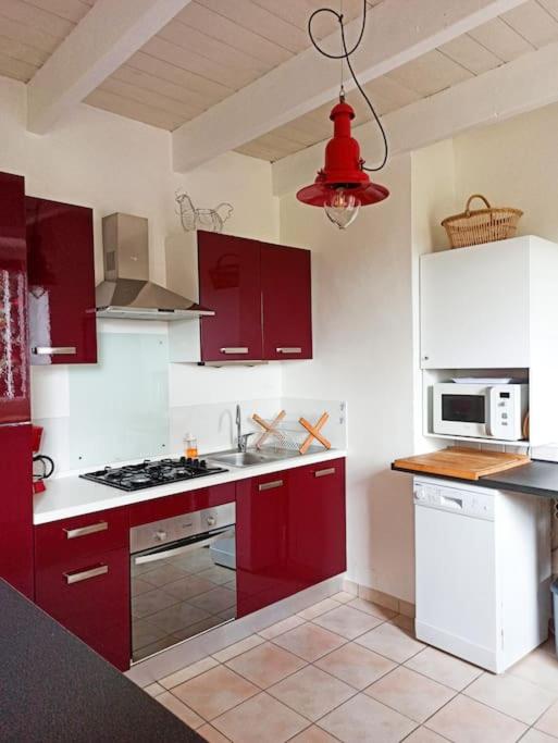 a kitchen with red cabinets and a red light at Maison de pêcheur rénovée (new) in Ploubazlanec