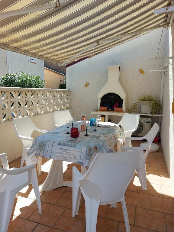 une table et des chaises blanches sur une terrasse avec une cheminée dans l'établissement Résidence LA GRAND VOILE, à Sainte-Marie-la-Mer