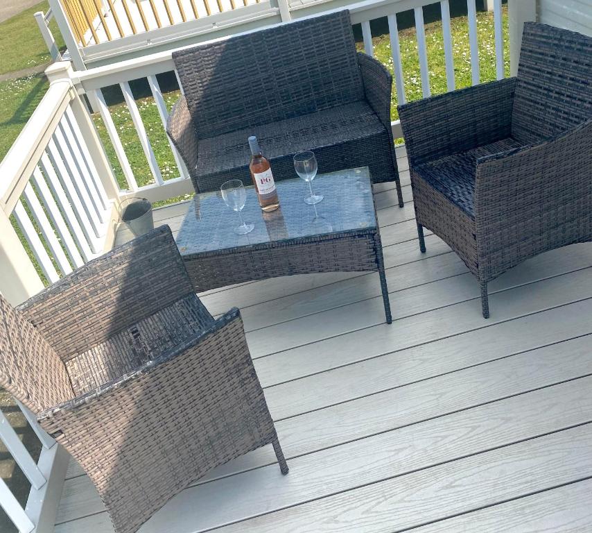 a patio with two chairs and a table with wine glasses at Cosy holiday home at Romney Sands in New Romney