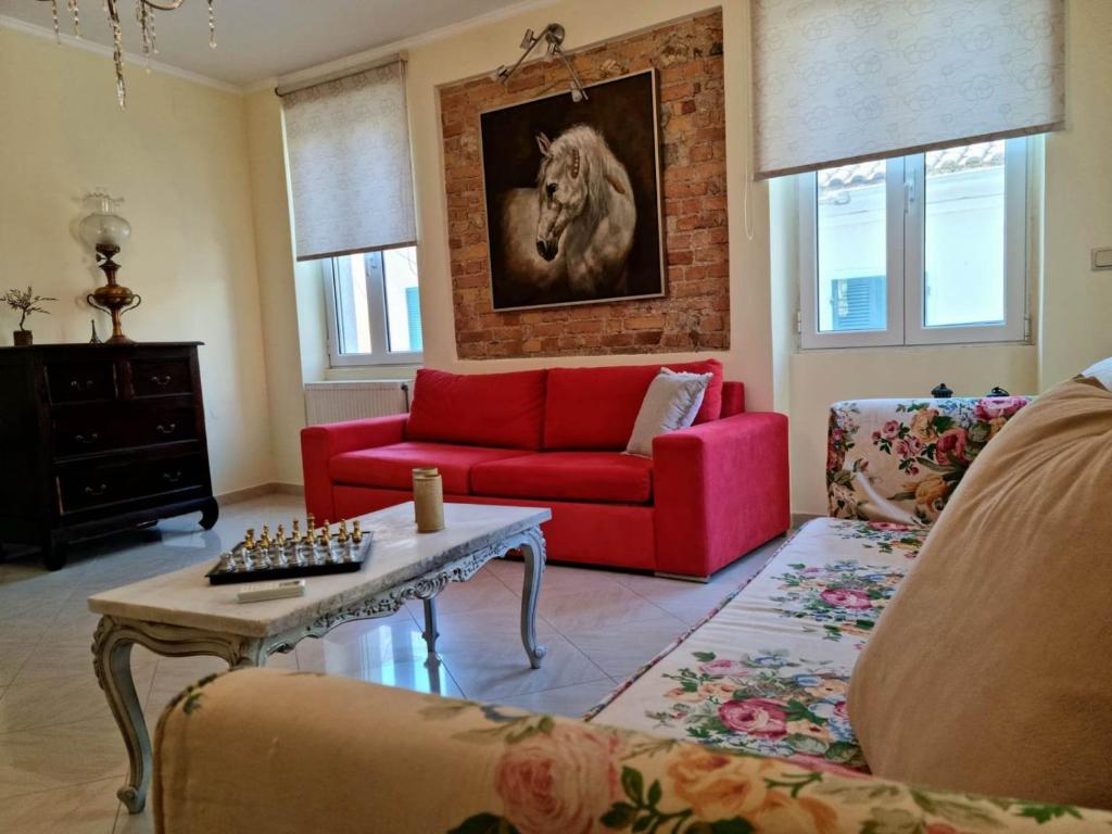 a living room with a red couch and a horse painting at Villa Maxim in Corfu Town in Anemómylos