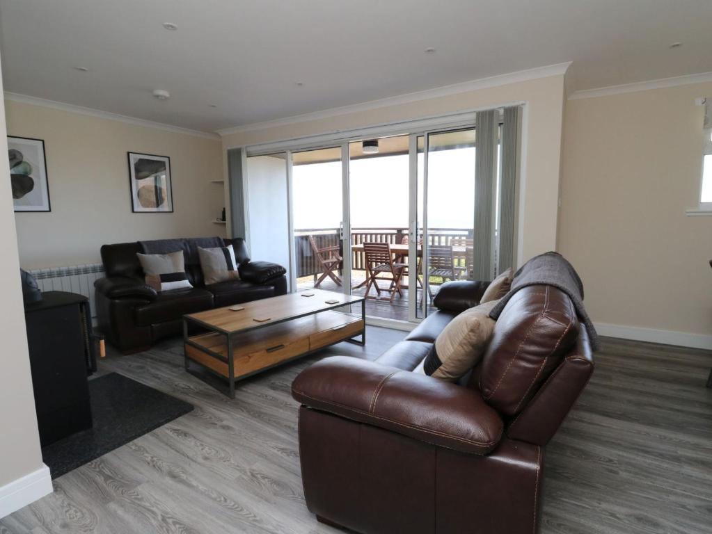 a living room with a leather couch and a table at Borve House, Kilchoan in Kilchoan