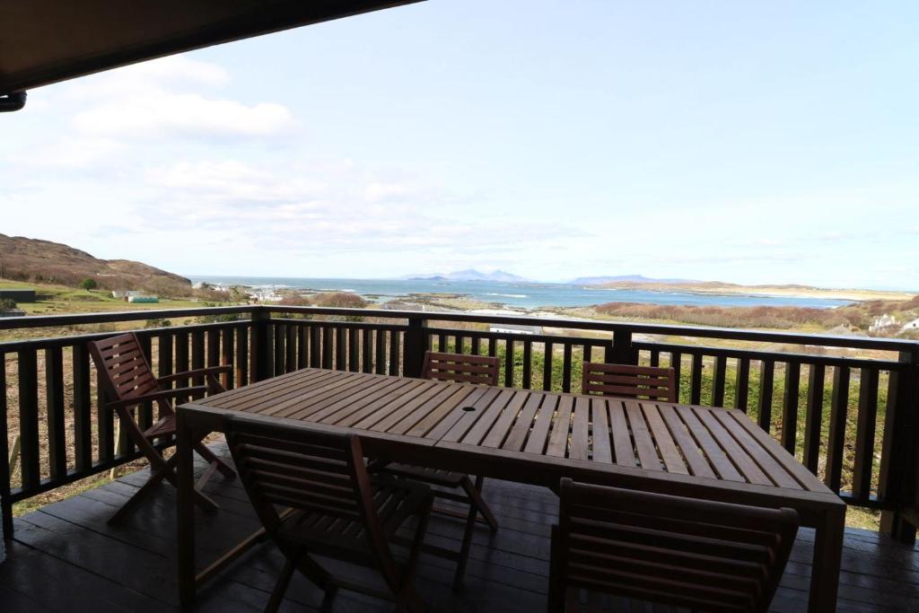 a wooden table and chairs on a balcony with a view at Borve House, Kilchoan in Kilchoan
