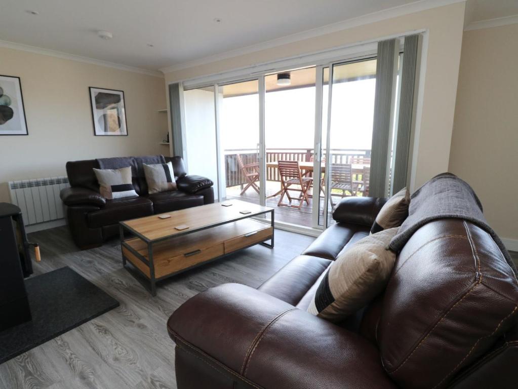 a living room with a leather couch and a coffee table at Borve House, Kilchoan in Kilchoan