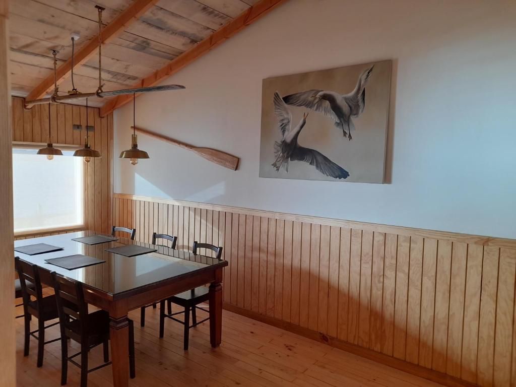 Portal de la Patagonia Austral في بويرتو مونت: غرفة طعام مع طاولة وطيور على الحائط