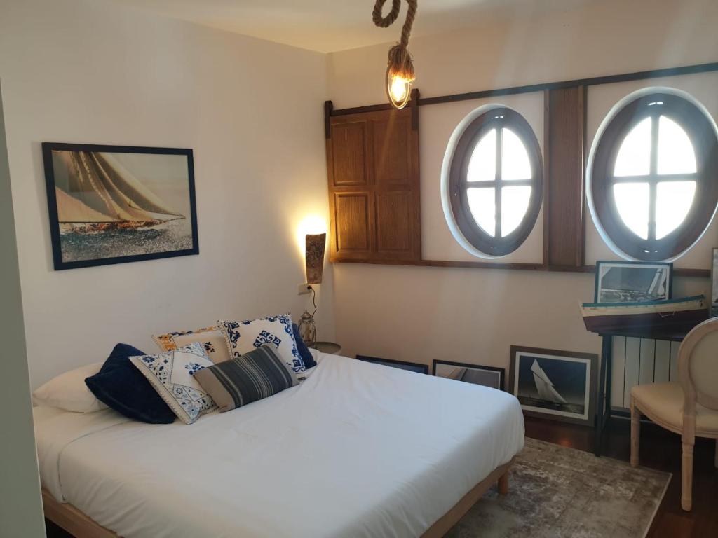 um quarto com uma cama branca e 2 janelas em Casa del Armiño Mansión de la Familia de "El Greco" em Toledo