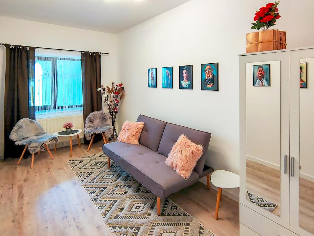 uma sala de estar com um sofá e duas cadeiras em 22 LOOP Apartment em Brasov