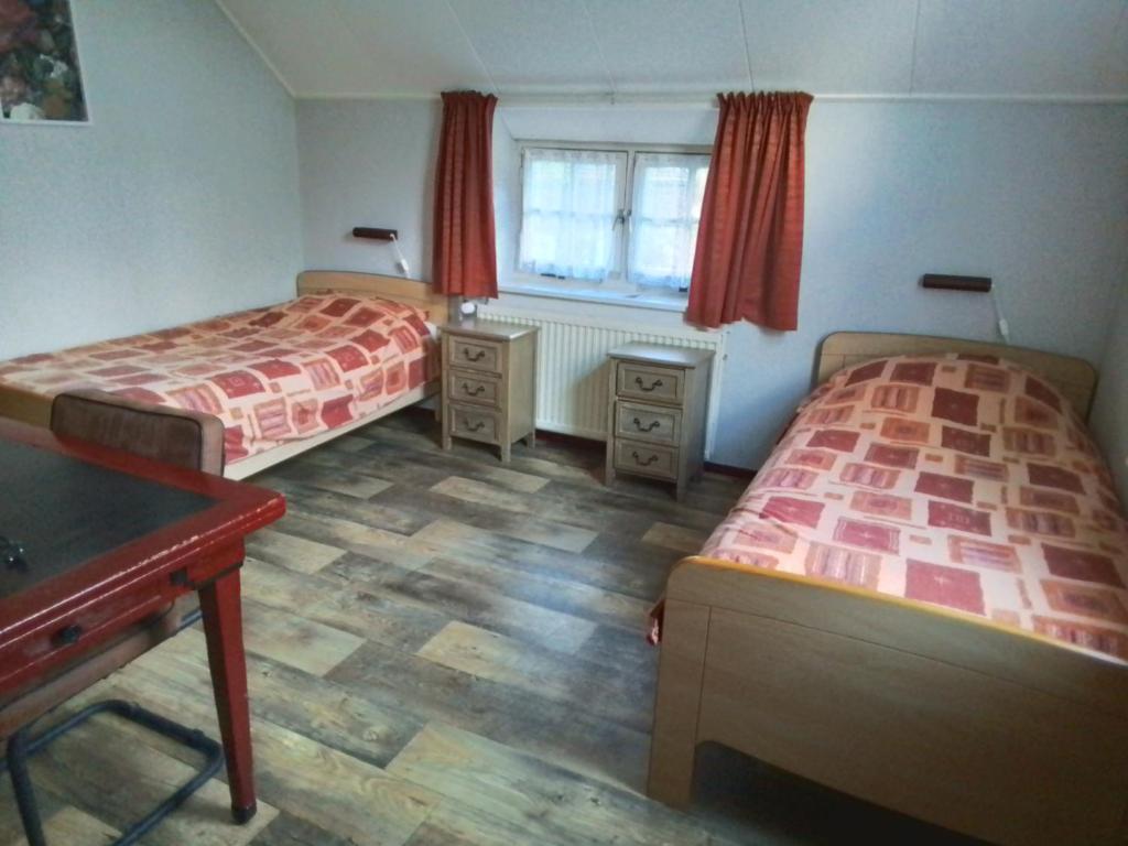 1 dormitorio con 2 camas, escritorio y ventana en Vakantiewoning 't Veurhuus en Bergentheim