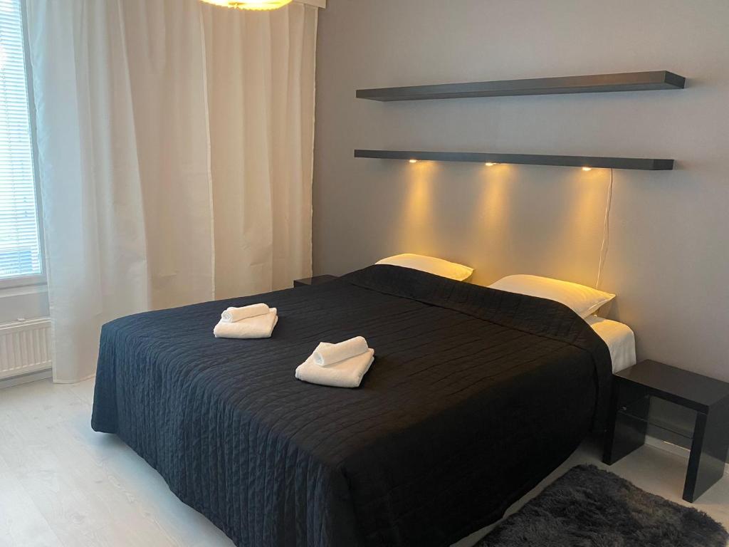 1 dormitorio con 1 cama negra y 2 toallas en Gella Serviced Apartments Office, en Helsinki