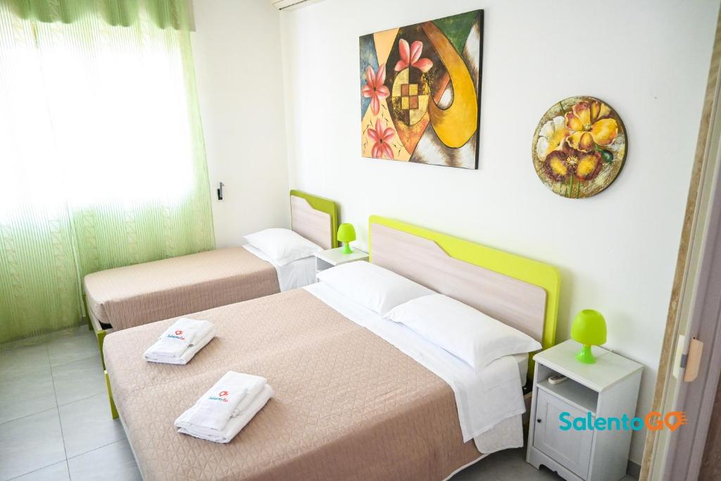 ein Hotelzimmer mit 2 Betten und einer Uhr an der Wand in der Unterkunft Appartamenti Jolly by SalentoGo in Torre Lapillo