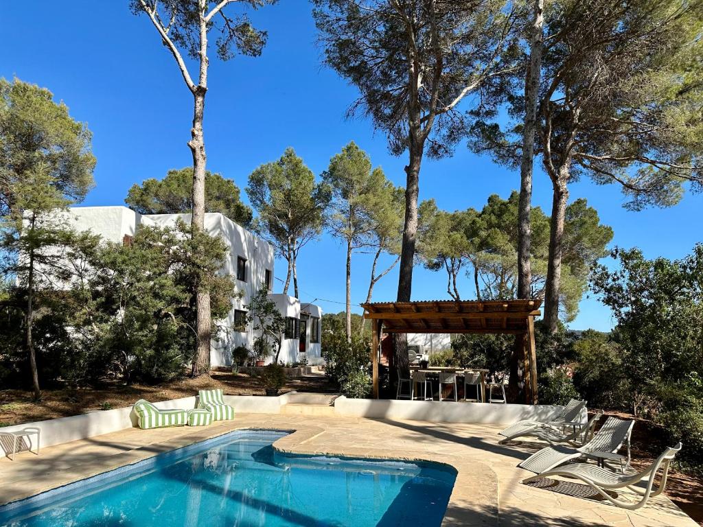 einen Pool mit Stühlen, einem Tisch und Bäumen in der Unterkunft Spacious & Luxury villa in centre Ibiza in Santa Gertrudis