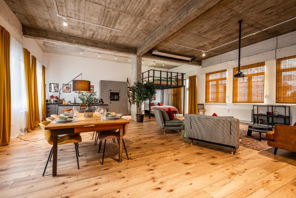 ein großes Wohnzimmer mit einem Holztisch und Stühlen in der Unterkunft Klassen Stay - Exklusives Loft - XXL Leinwand - 4 km Messe, 1,5 km HBF in Essen