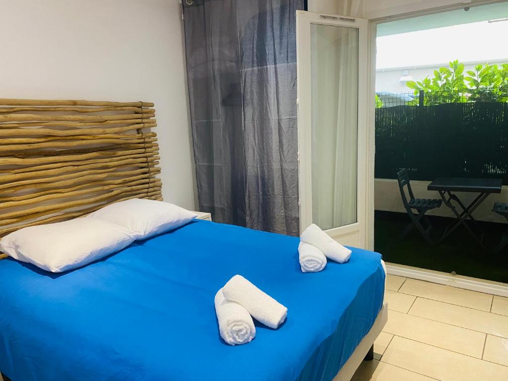 - une chambre avec un lit bleu et 2 serviettes dans l'établissement Magnifique T2 en bord de mer, au Lavandou