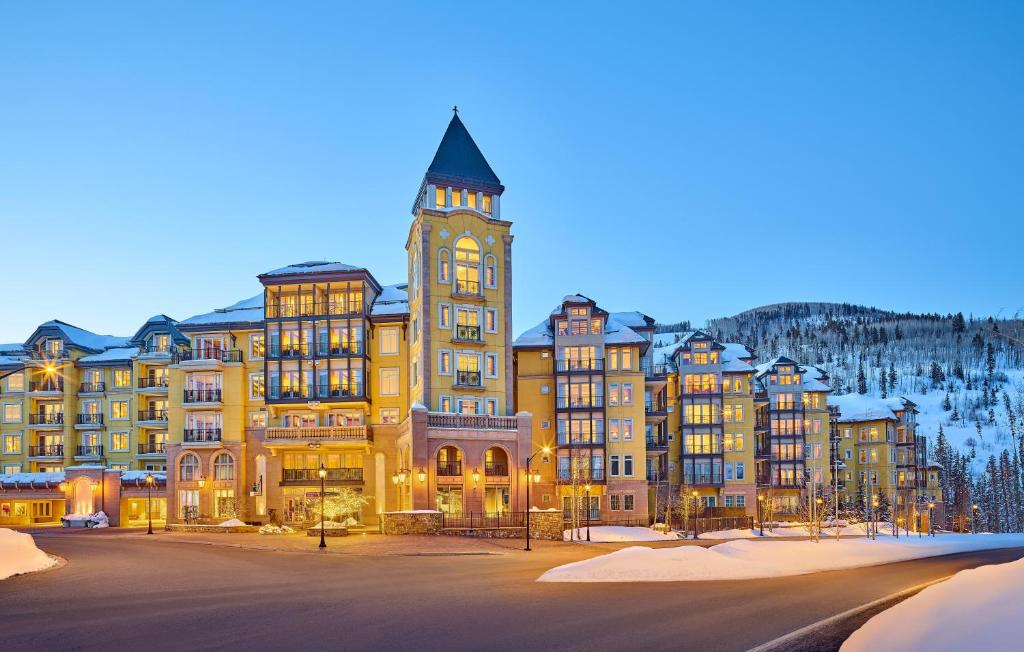 a large building with a clock tower in the snow at The Vail Collection at the Ritz Carlton Residences Vail in Vail