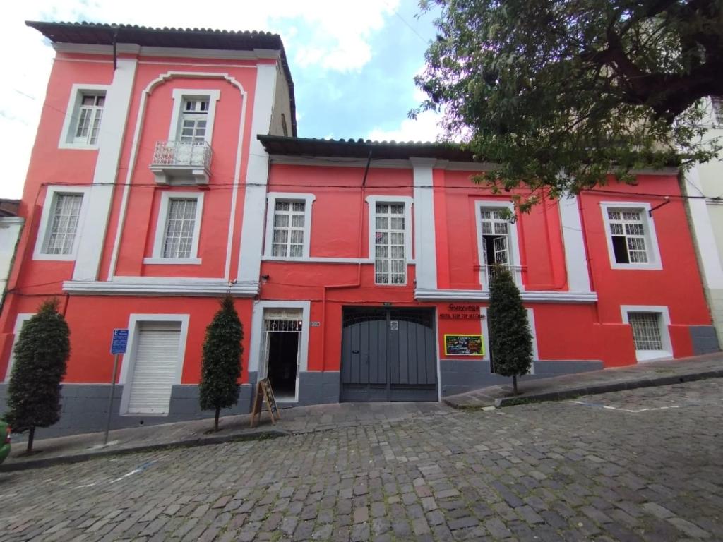 un edificio rojo y blanco con entrada en Hostal La Guayunga RoofTop, en Quito