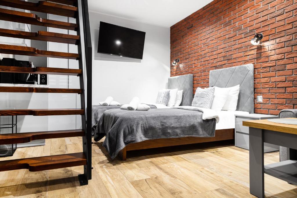 a bedroom with a bed and a brick wall at HOUSEHOST Apartment:Bracka 3/15B in Krakow