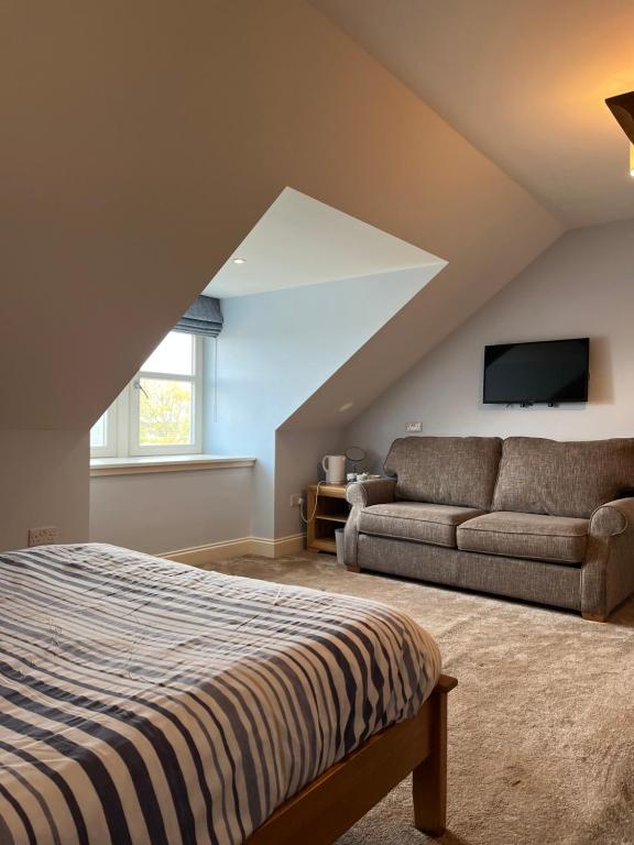 a attic bedroom with a bed and a couch at Corsee House in Nairn