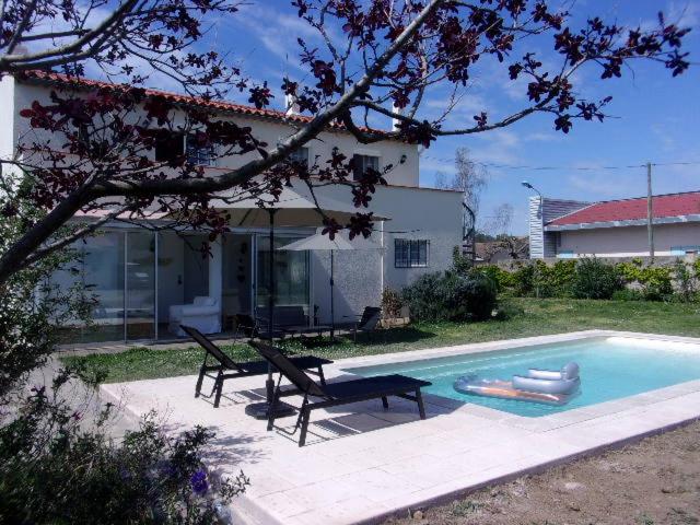 a swimming pool with a bench and a house at Appartement du Pont neuf in Villegailhenc