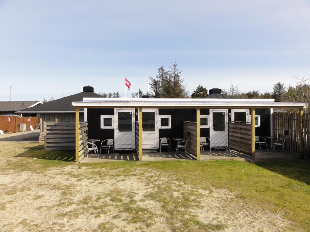 a black and white mobile home with chairs in a yard at Tornby Strand Camping Rooms in Hirtshals