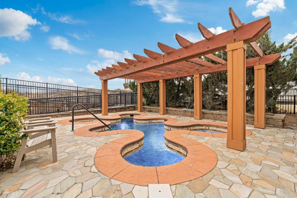 a patio with a wooden pergola and a pool at Croatan Surf Club by KEES Vacations in Kill Devil Hills