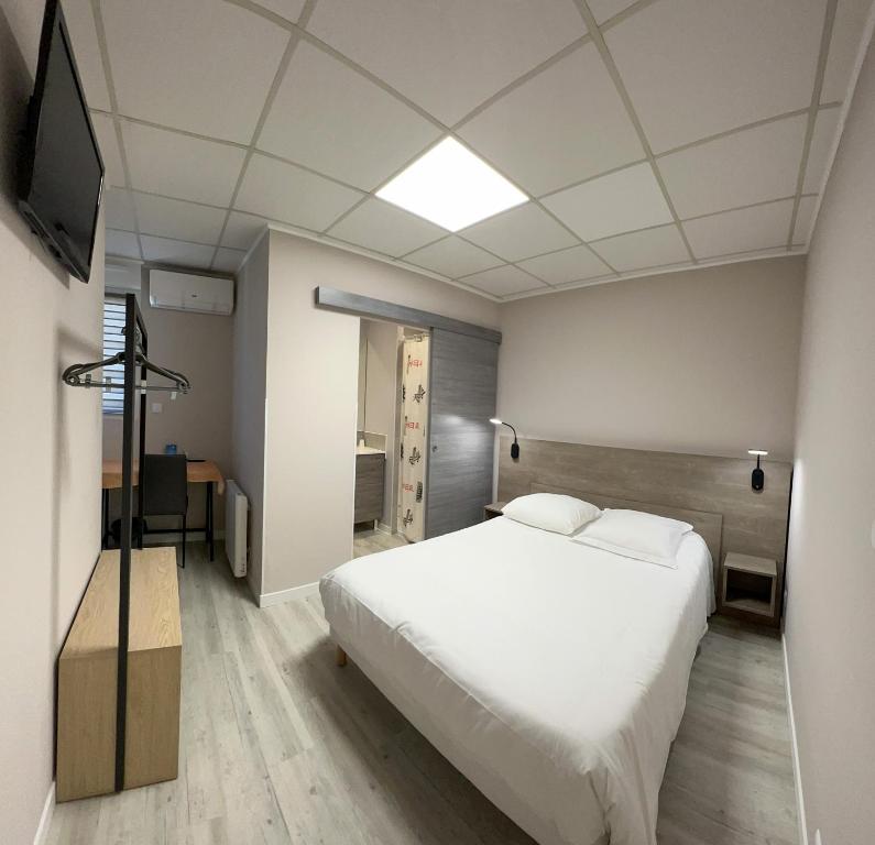 um quarto com uma cama branca e uma televisão em Le Petit Logis em Beaumont-en-Véron