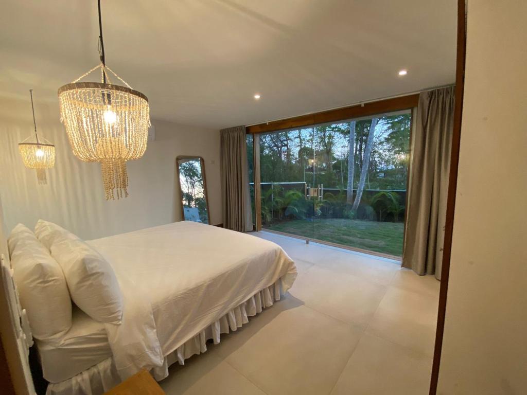 a bedroom with a white bed and a large window at Villa Laia - Santa Teresa in Santa Teresa Beach