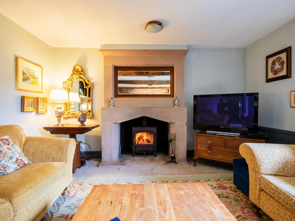 a living room with a fireplace and a tv at The Farmhouse in Bakewell