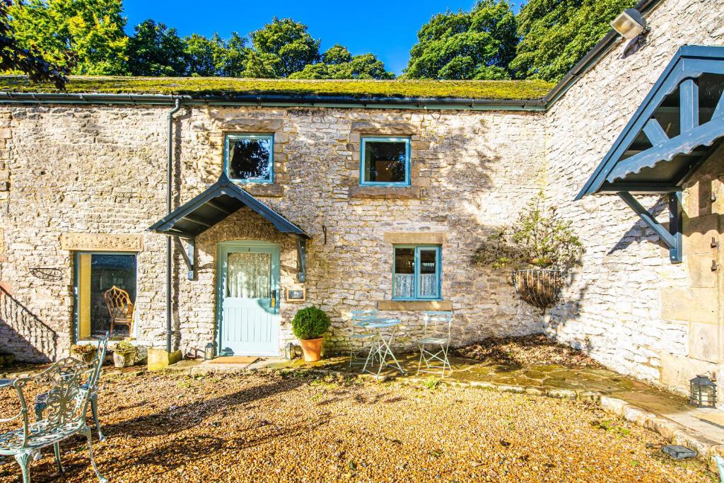 a stone house with a door and chairs in a yard at Fruitpip in Bakewell