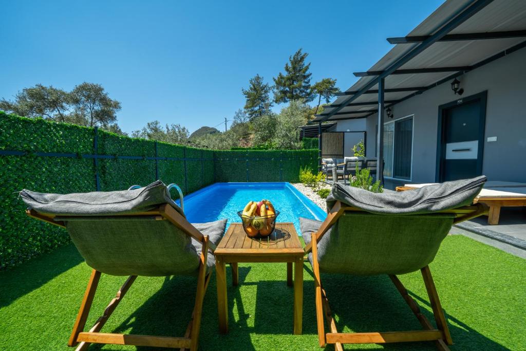 einen Hinterhof mit zwei Stühlen, einem Tisch und einem Pool in der Unterkunft Santana Villas in Göcek