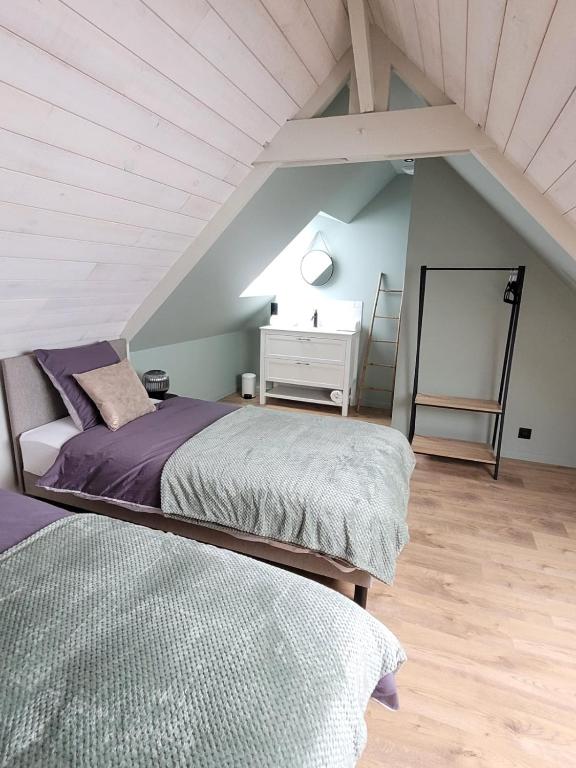 sypialnia na poddaszu z dwoma łóżkami i białą komodą w obiekcie le jardin médicis gîte avec Spa Jacuzzi et sauna w mieście Trédion