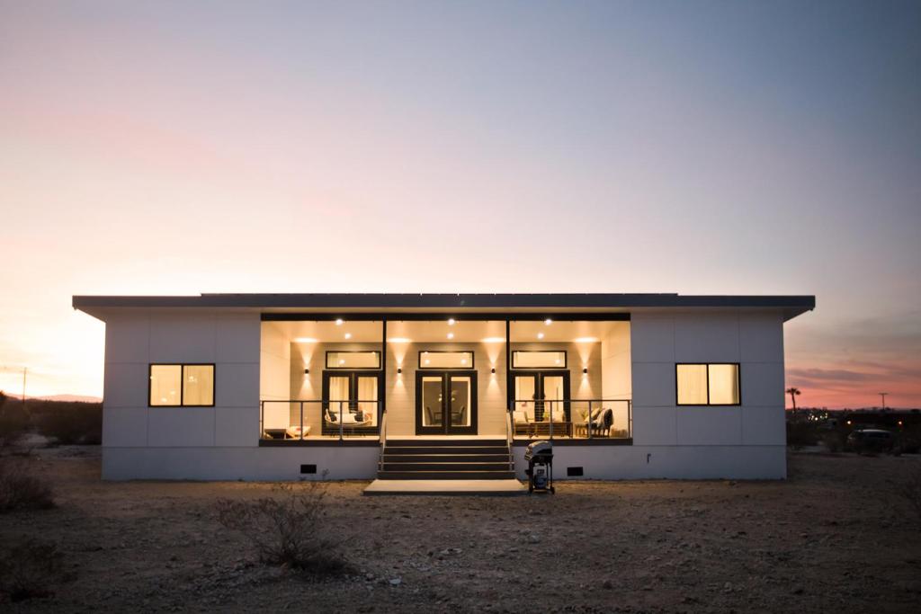 una gran casa blanca con una puesta de sol en el fondo en Modern Desert Dream - NEW BUILD, en Twentynine Palms