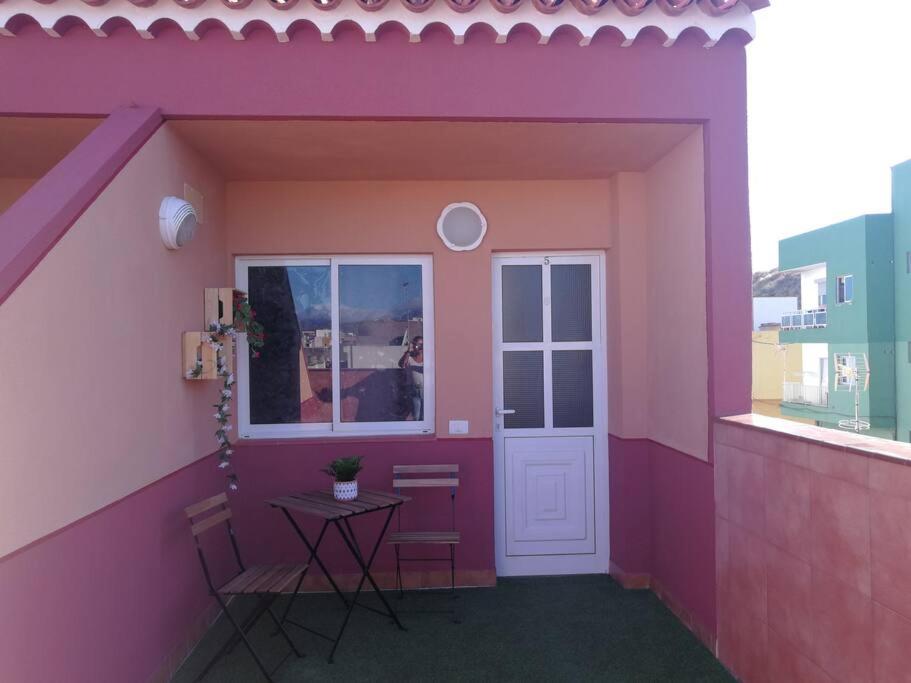 een roze kamer met een tafel en een raam bij ACOGEDOR ATICO CON TERRAZA EN SAN CRISTOBAL DE LA LAGUNA in La Laguna