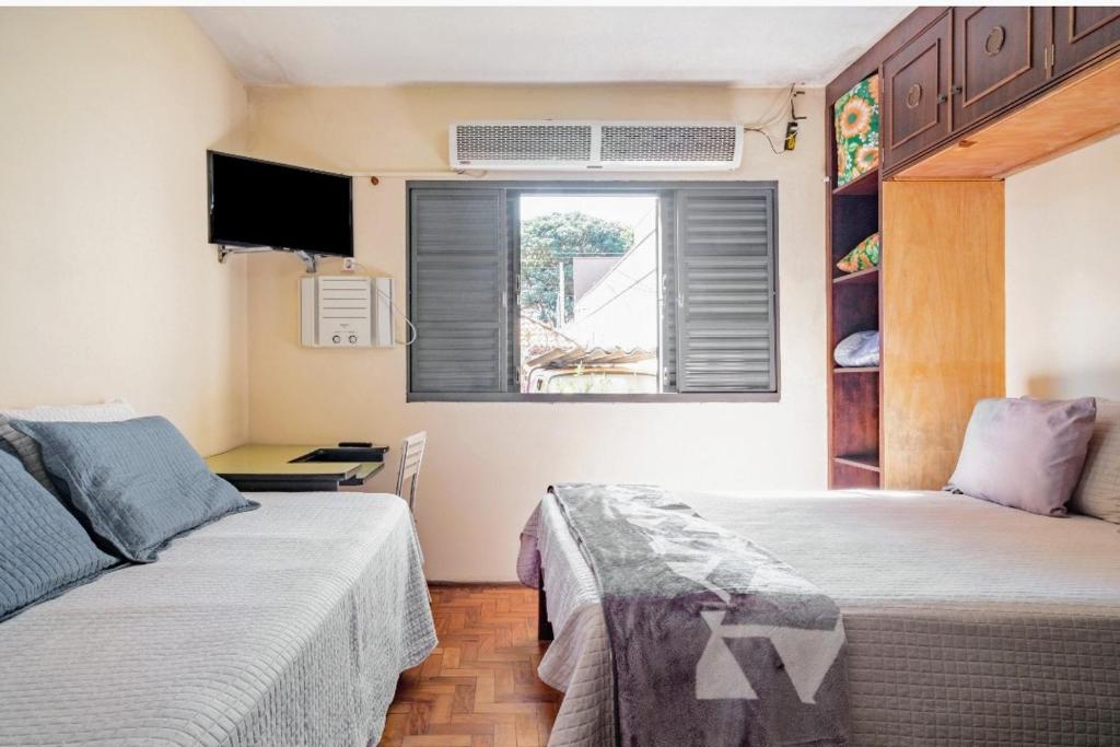 um pequeno quarto com 2 camas e uma janela em Suite com ar em Jaú