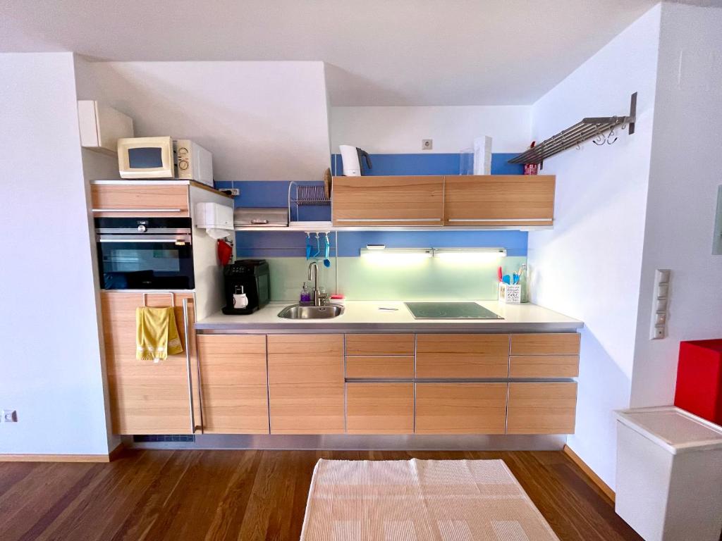 una piccola cucina con armadi in legno e lavandino di Una a Vienna