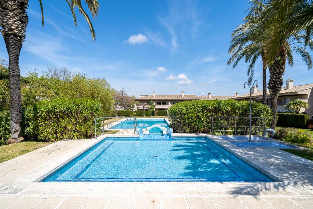 a swimming pool in a yard with palm trees at Hauzify I Apartament Bòvila Mar in S'agaro