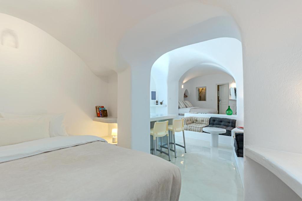 a white hotel room with a bed and a desk at Crown of Fira in Firostefani