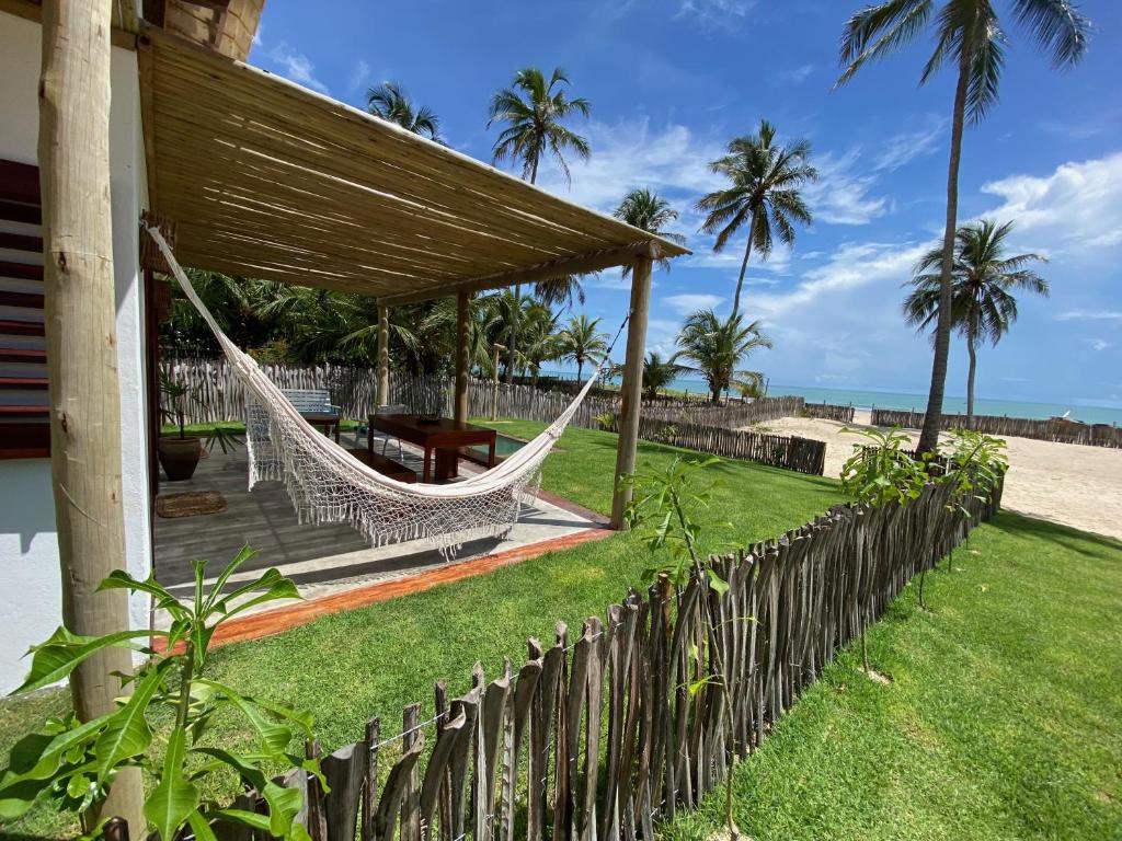 a hammock on the side of a house next to the beach at Os Navegantes - Casa Mar in Amontada