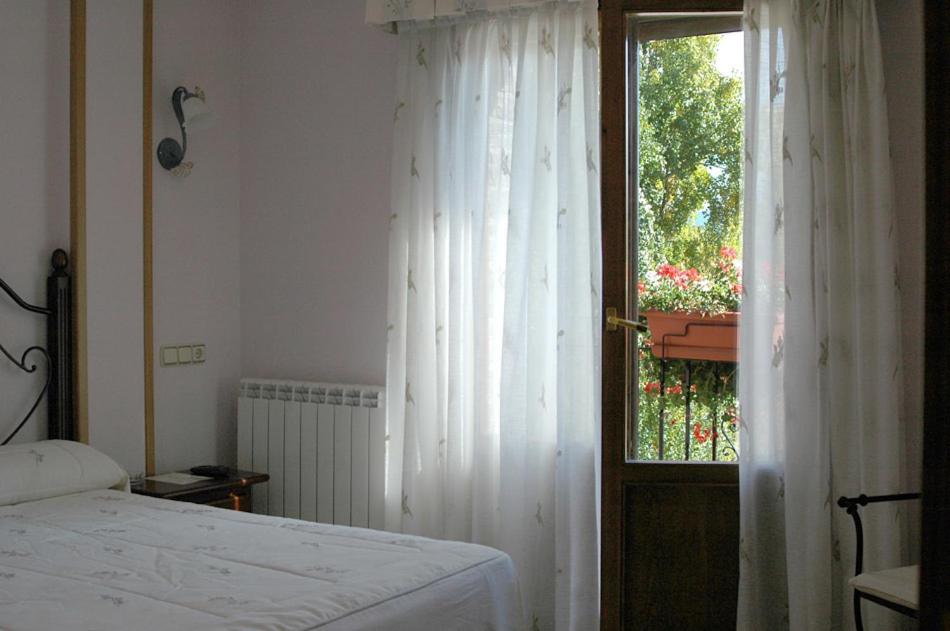 a bedroom with a bed and a window with white curtains at Hotel Restaurante Santa Elena in Sabiñánigo