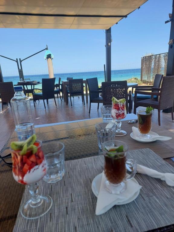 stół z kieliszkami napojów na stole z plażą w obiekcie Appartement Residence Essayedi Sousse w mieście Port El Kantaoui