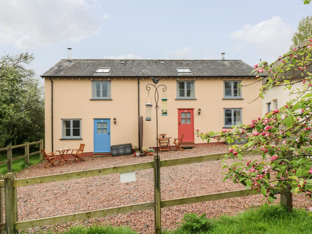 a house with red doors and a fence at Apple Cottage in Crediton