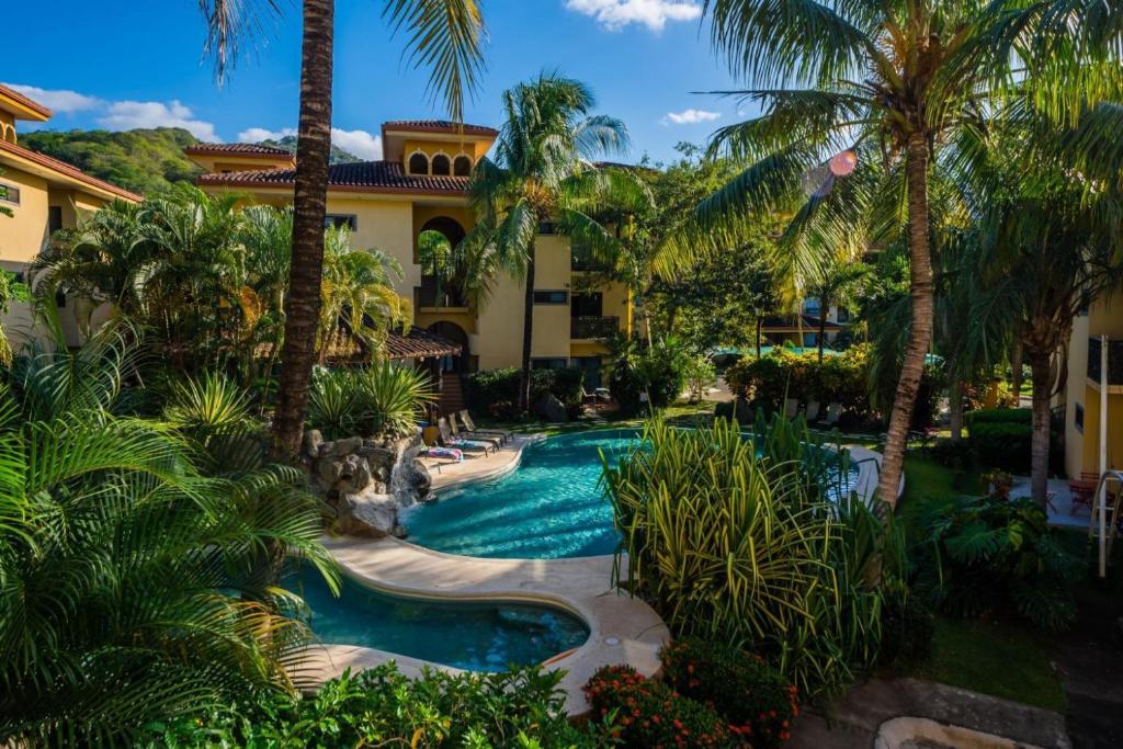 un complejo con piscina y palmeras en Beautiful newly refurbished 2 bedroom 2 Bathroom 2nd floor condo en Tamarindo