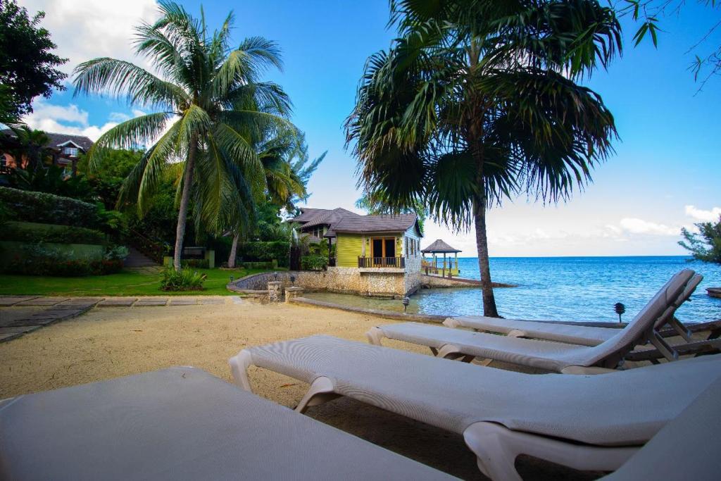 a group of lounge chairs on a beach next to the ocean at Crystal Cove Oceanfront/ 2 bedroom Condo in Ocho Rios