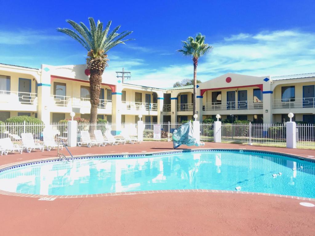 a swimming pool in front of a hotel with palm trees at Americas Best Value Inn Beaumont in Beaumont