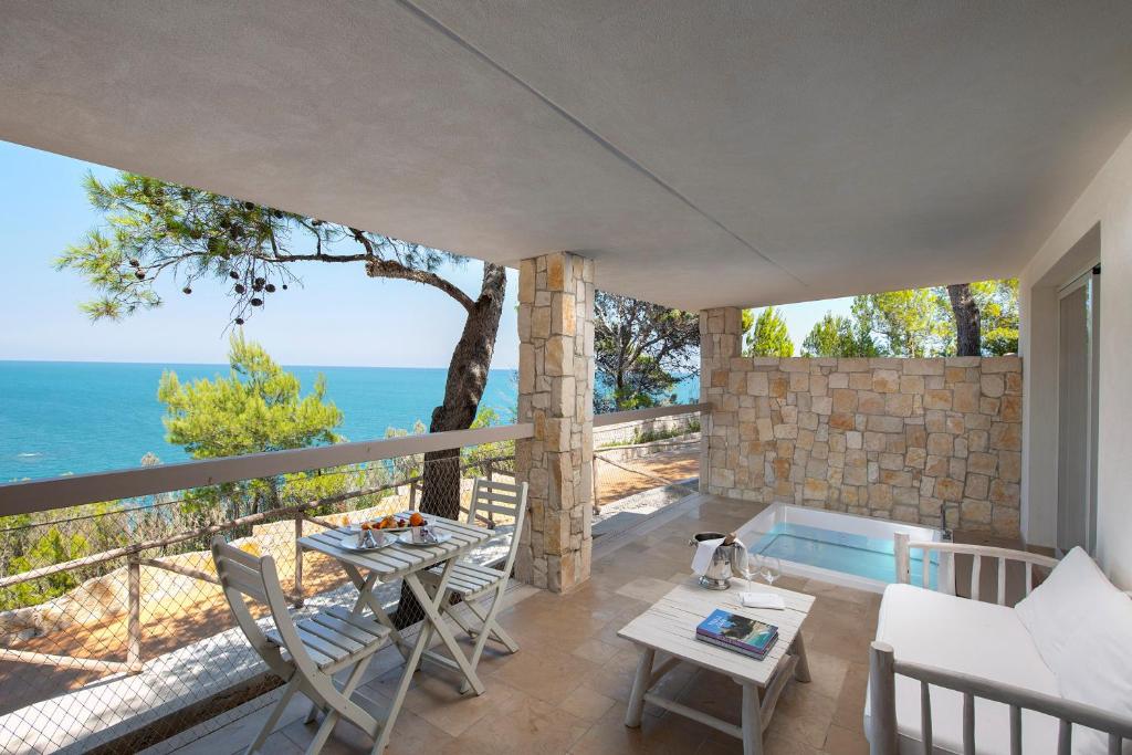 un patio con tavolo, sedie e vista sull'oceano di Gattarella Family Resort - Premium Half-Board à la carte a Vieste