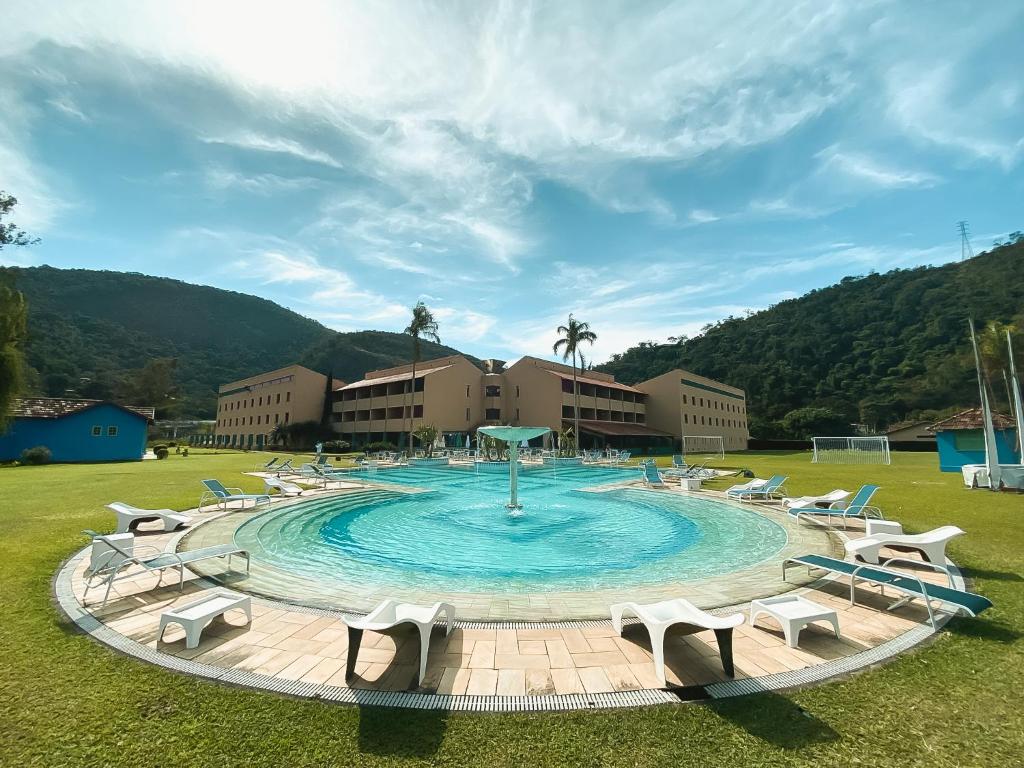 una gran piscina con sillas alrededor en un campo en Villa Itaipava Resort & Conventions en Itaipava