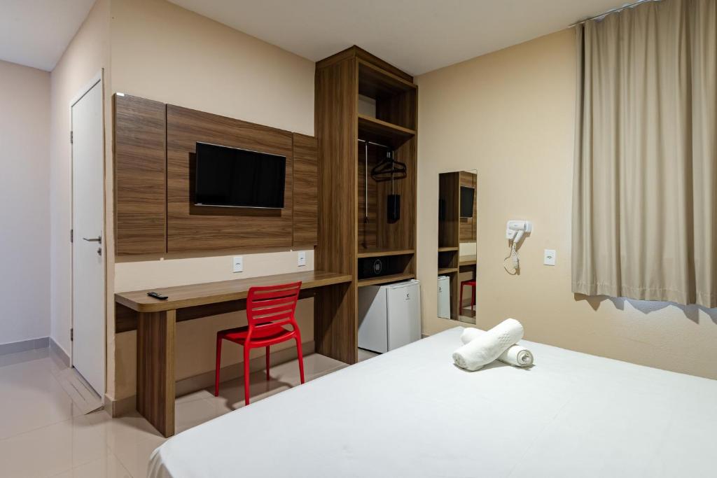 a hotel room with a desk and a red chair at Hotel Santos Dumont Aeroporto SLZ in São Luís