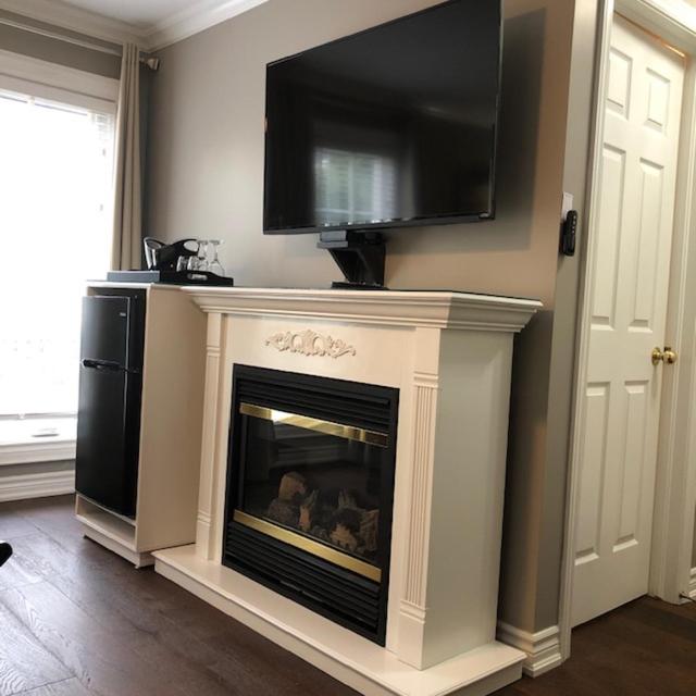 a living room with a fireplace with a television above it at Casa Blanca Boutique Bed & Breakfast in Niagara-on-the-Lake