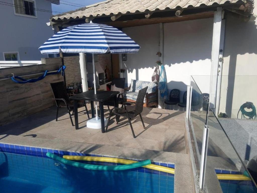 un patio con mesa y sombrilla junto a la piscina en Recanto do Sul - Campeche, en Florianópolis